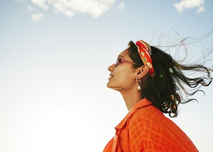 Side view of a young woman looking up at the sky and smiling during a sunny day in summer