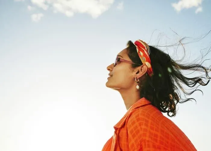 Side view of a young woman looking up at the sky and smiling during a sunny day in summer
