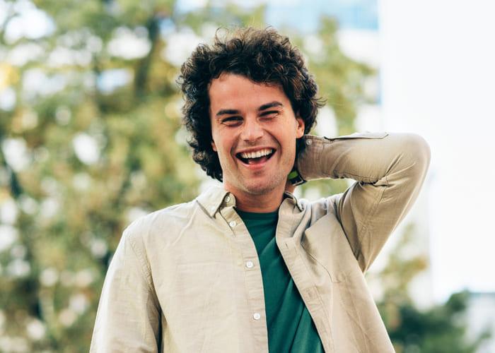 Handsome smiling young man posing for advertisement and looking at the camera. Portrait of smart male has joyful expression.