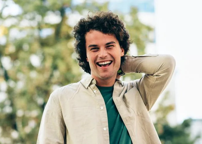 Handsome smiling young man posing for advertisement and looking at the camera. Portrait of smart male has joyful expression.