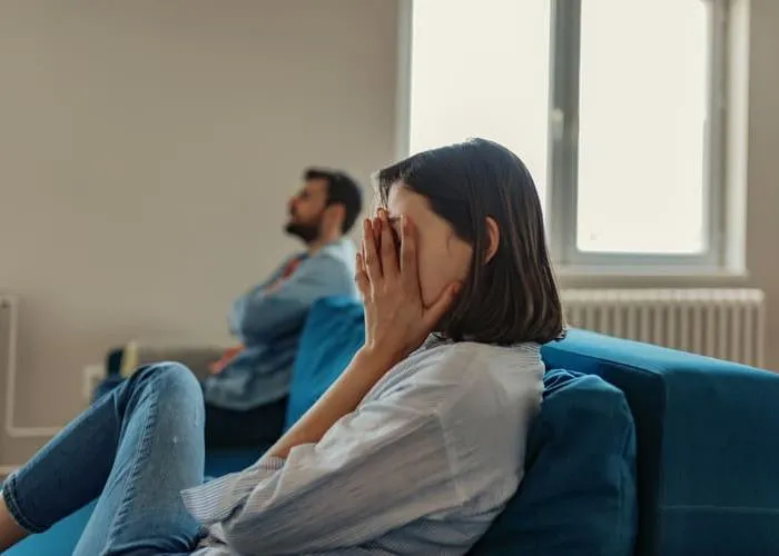 Unhappy Couple After an Argument in the Living Room at Home. Sad Pensive Young Girl Thinking of Relationships Problems Sitting on Sofa With Offended Boyfriend, Conflicts in Marriage, Upset Couple After Fight Dispute, Making Decision of Breaking Up Get Div