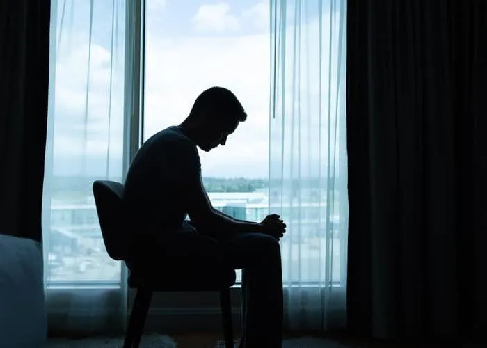Lonely and sad man sitting in the dark room by  himself.